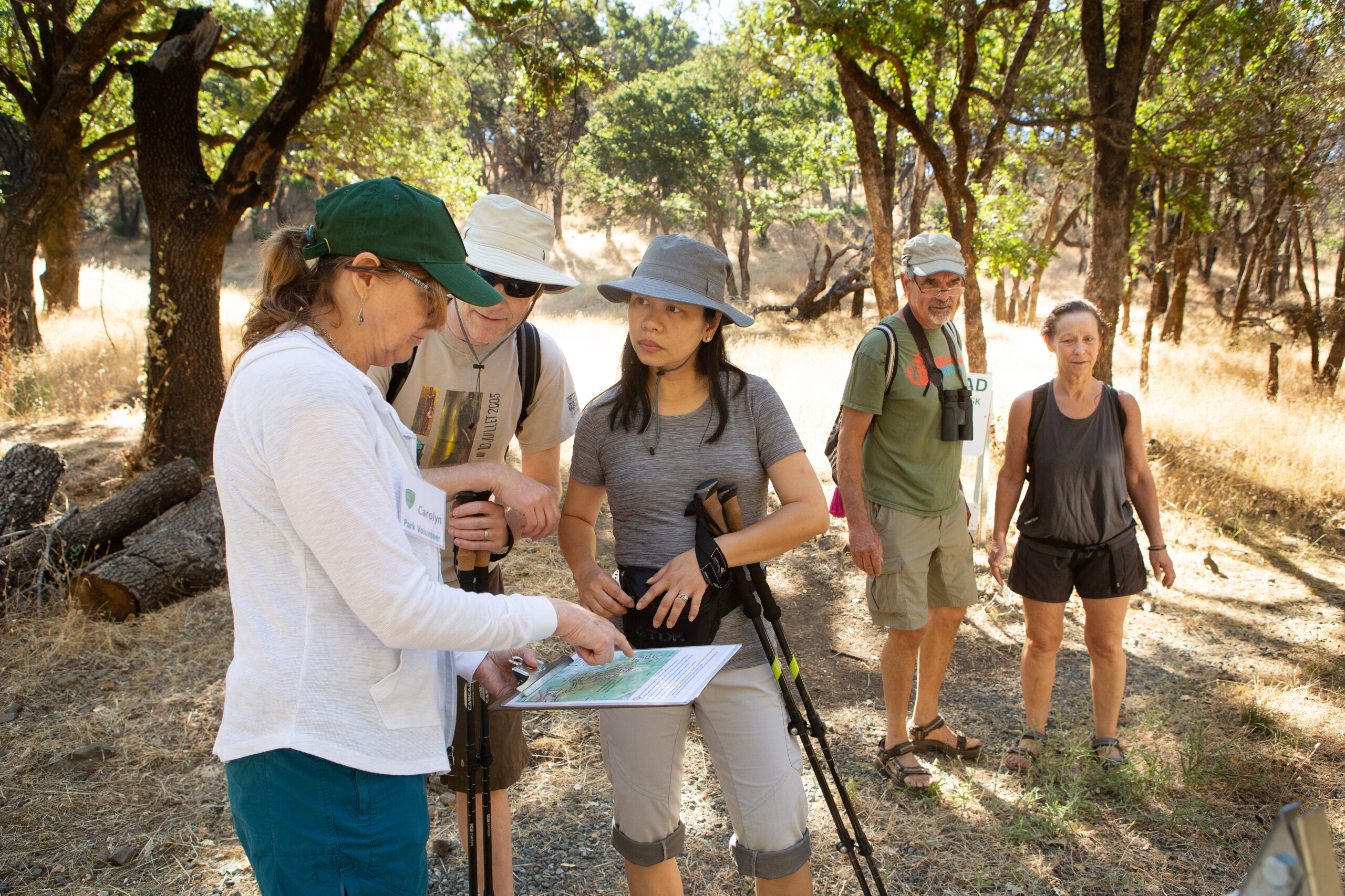 A volunteer for Sonoma County Regional Parks and a park visitor look at a map together while standing on a trail.